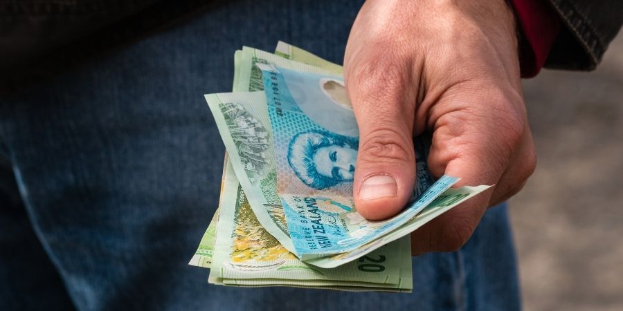 Hombre con dolares neozelandeses en la mano
