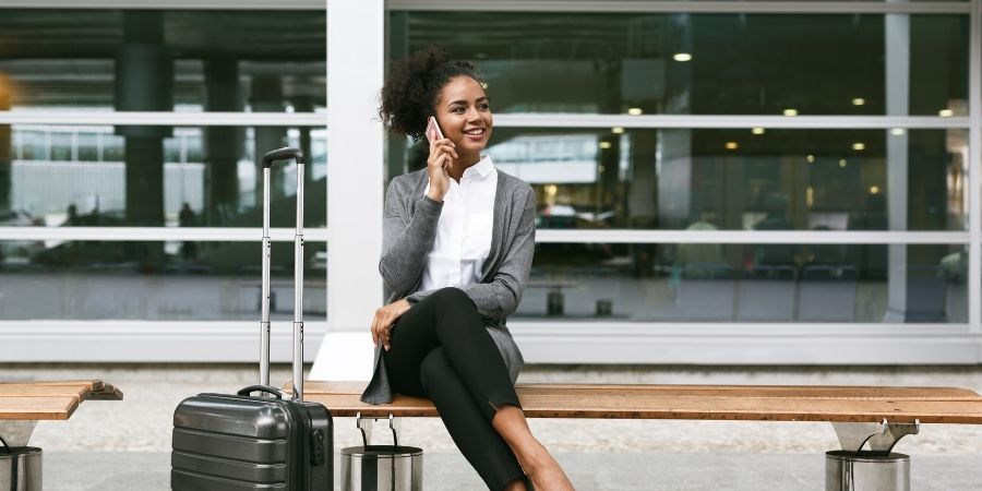 Mujer con una maleta charlando por telefono en viaje a nueva zelanda